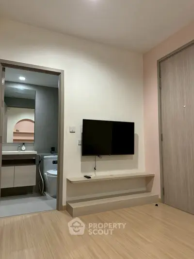 Modern living room with wall-mounted TV and view into a sleek bathroom