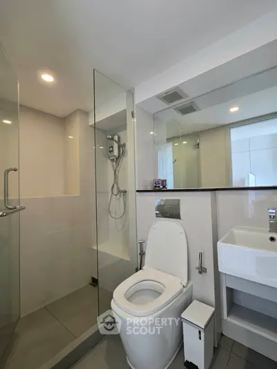 Modern bathroom with glass shower and sleek fixtures in contemporary apartment.