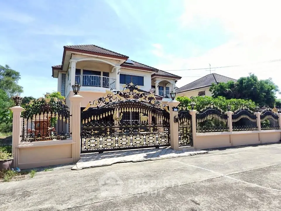Elegant two-story house with ornate iron gate and lush greenery, showcasing luxury and privacy.
