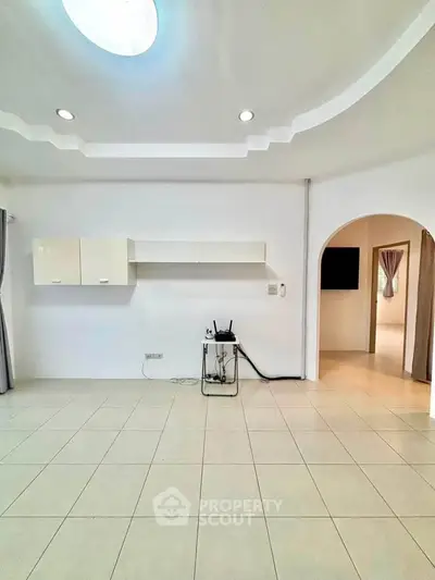 Spacious living room with modern ceiling design and tiled flooring, perfect for family gatherings.