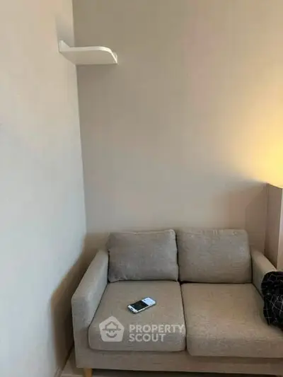 Cozy living room corner with a modern gray sofa and wall shelf, perfect for relaxation.