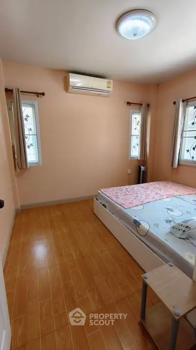 Cozy bedroom with wooden flooring and air conditioning, perfect for relaxation.