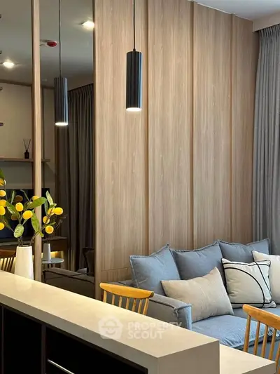 Modern living room with stylish decor and cozy seating area, featuring pendant lighting and wooden accents.