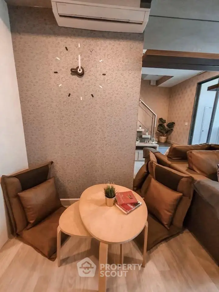 Cozy living room corner with stylish wall clock and comfortable seating, perfect for relaxation.