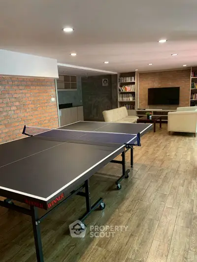 Spacious recreation room with ping pong table and cozy seating area, perfect for entertainment.