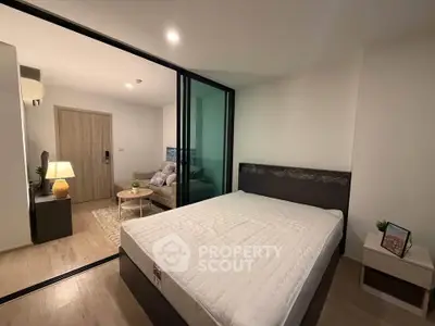 Modern bedroom with glass partition and cozy living area, perfect for urban living.