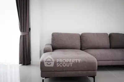 Modern living room with stylish gray sofa and elegant curtains, perfect for cozy relaxation.