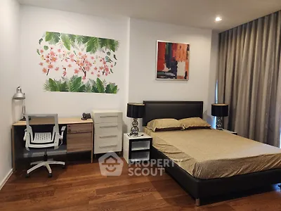 Modern bedroom with stylish decor and workspace, featuring wooden flooring and elegant curtains.