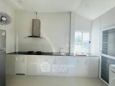 Modern kitchen with sleek design and gas stove, featuring ample natural light and minimalist cabinetry.