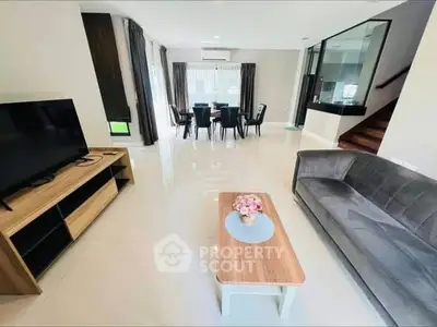 Spacious modern living room with sleek furniture and open dining area, perfect for family gatherings.