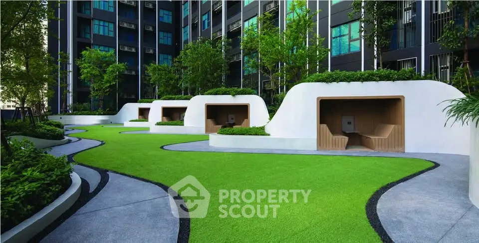 Modern apartment complex with lush garden and unique seating areas.