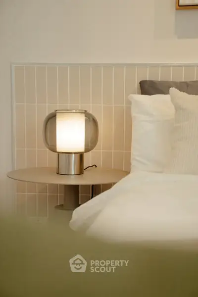 Elegant bedroom with modern lamp and cozy bedding, perfect for relaxation.