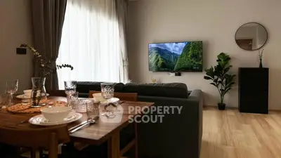 Modern living room with stylish decor and dining area, featuring a wall-mounted TV and large window.