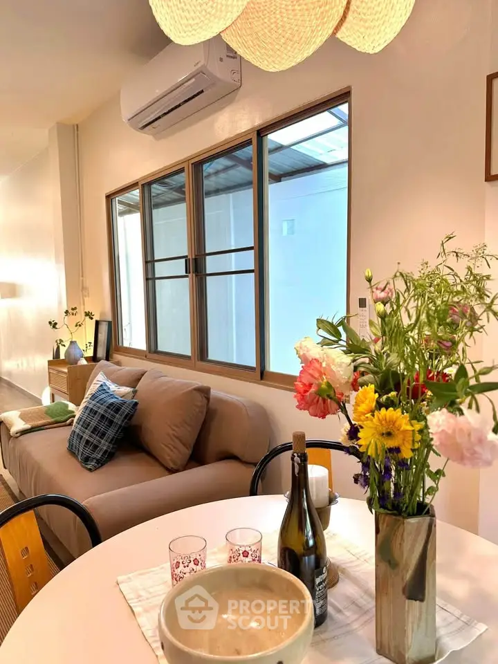 Charming living room with cozy sofa, air conditioning, and vibrant floral decor.