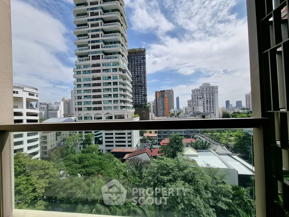 Stunning cityscape view from a high-rise apartment window, showcasing modern architecture and lush greenery.