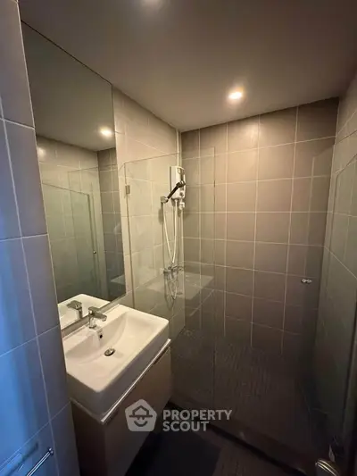 Modern bathroom with sleek glass shower and stylish sink in contemporary apartment.