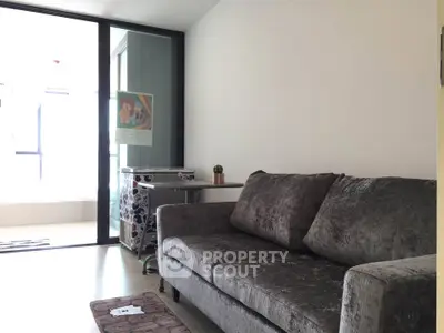 Modern living room with plush gray sofa and large windows offering natural light.