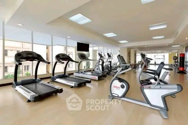 Spacious modern gym with state-of-the-art equipment and large windows for natural light.