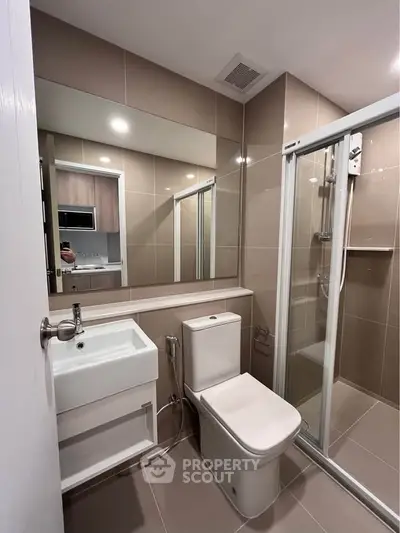 Modern bathroom with sleek design, featuring a glass shower enclosure and contemporary fixtures.