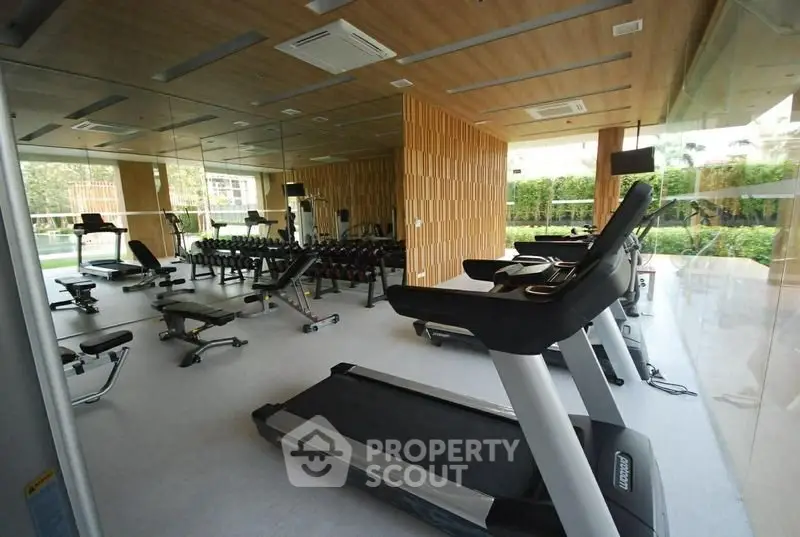 Modern gym with state-of-the-art equipment and mirrored walls in luxury residential complex.
