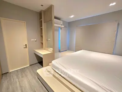 Modern minimalist bedroom with sleek design and neutral tones, featuring built-in storage and large windows.