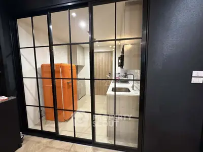 Modern kitchen with glass sliding doors and vibrant orange fridge