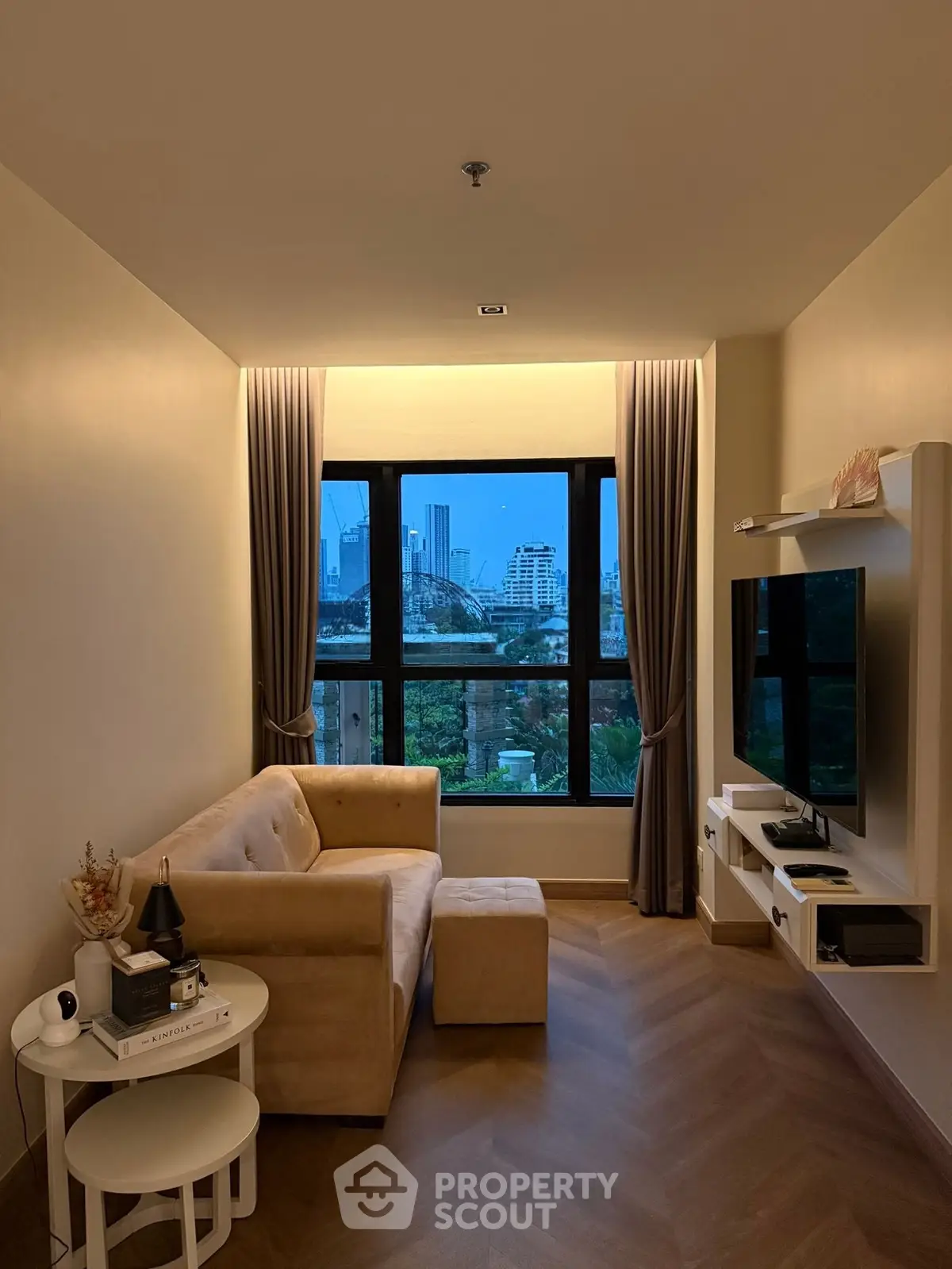 Modern living room with city view, cozy sofa, and entertainment setup in a stylish apartment.