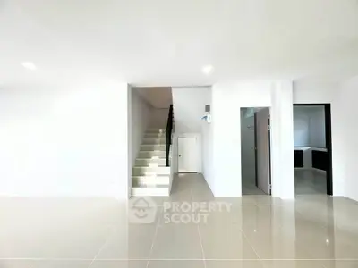 Spacious modern interior with sleek staircase and tiled flooring, ideal for contemporary living.