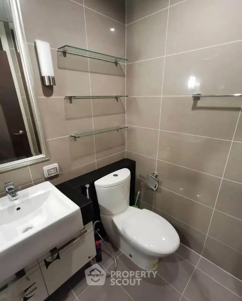 Modern bathroom with sleek fixtures and neutral tiles, featuring a toilet and sink.