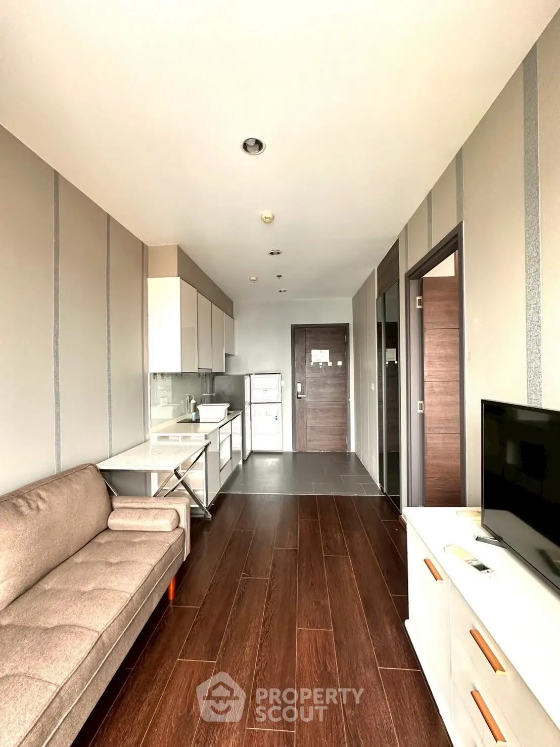 Modern apartment interior with sleek kitchen and cozy living area, featuring wooden flooring and contemporary design.