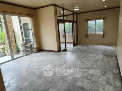 Spacious living room with marble flooring and large windows for natural light.