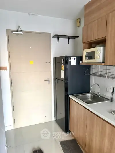 Compact kitchen with modern appliances and sleek cabinetry in a cozy apartment.