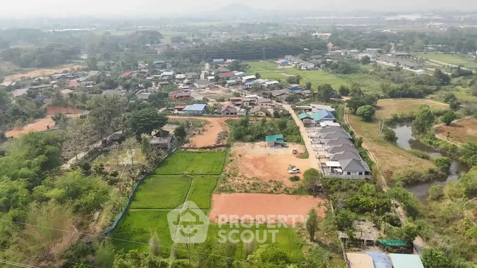 Aerial view of a residential area with green fields and houses, showcasing serene countryside living.