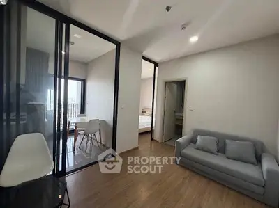 Modern apartment interior with glass partition, cozy living area, and wooden flooring.