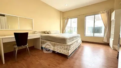 Spacious bedroom with large windows and wooden flooring, perfect for natural light lovers.