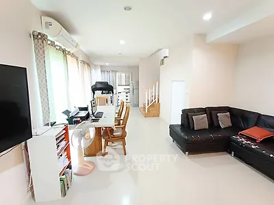 Spacious modern living room with sleek black sofa and dining area, perfect for family gatherings.