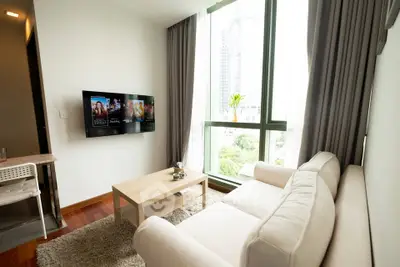 Modern living room with large windows and cozy seating in a high-rise apartment.