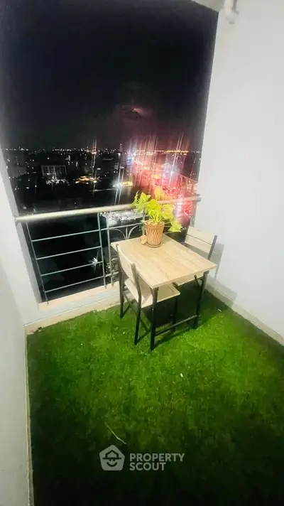 Charming balcony with artificial grass and city night view, perfect for relaxation.