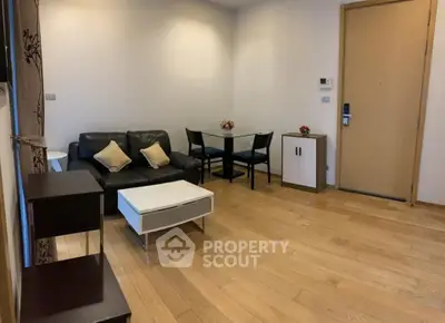 Modern living room with wooden flooring, black sofa, and dining area in a cozy apartment.