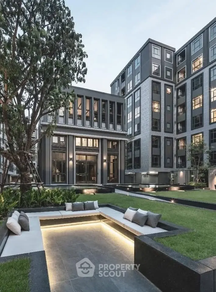 Modern apartment complex with landscaped garden and seating area, showcasing contemporary architecture.