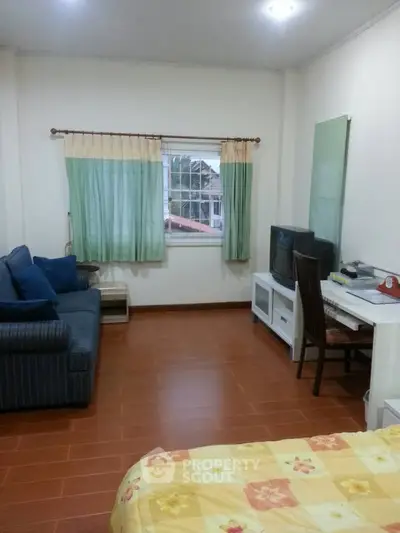 Cozy living room with sofa, TV, and study desk, ideal for relaxation and work.