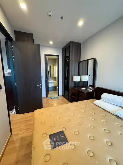 Modern bedroom with stylish furniture and ensuite bathroom in a contemporary apartment.