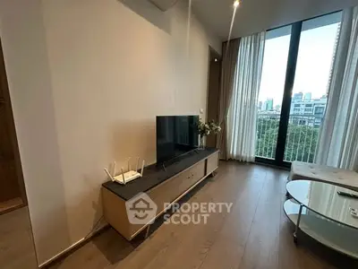 Modern living room with sleek TV stand and large windows offering city views.