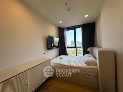 Modern bedroom with city view, featuring a mounted TV and stylish furniture.