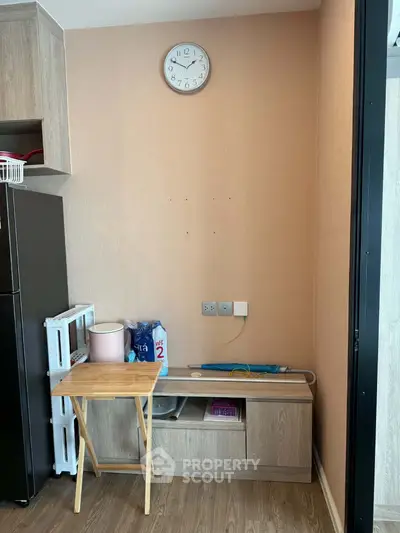 Modern interior with wooden flooring, wall clock, and compact storage unit in cozy living space.