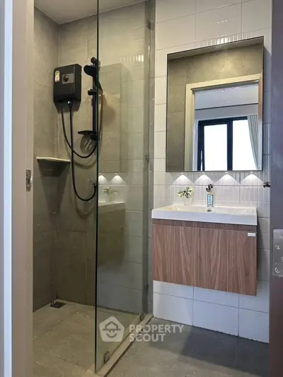 Modern bathroom with glass shower and sleek vanity in contemporary apartment.
