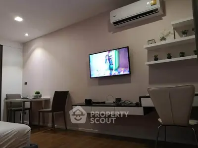 Modern living room with wall-mounted TV and sleek furniture in a cozy apartment.