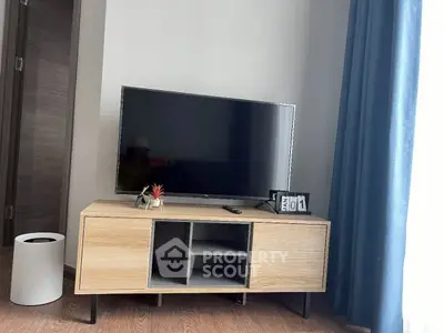 Modern living room with stylish TV stand and flat-screen TV, complemented by elegant curtains.