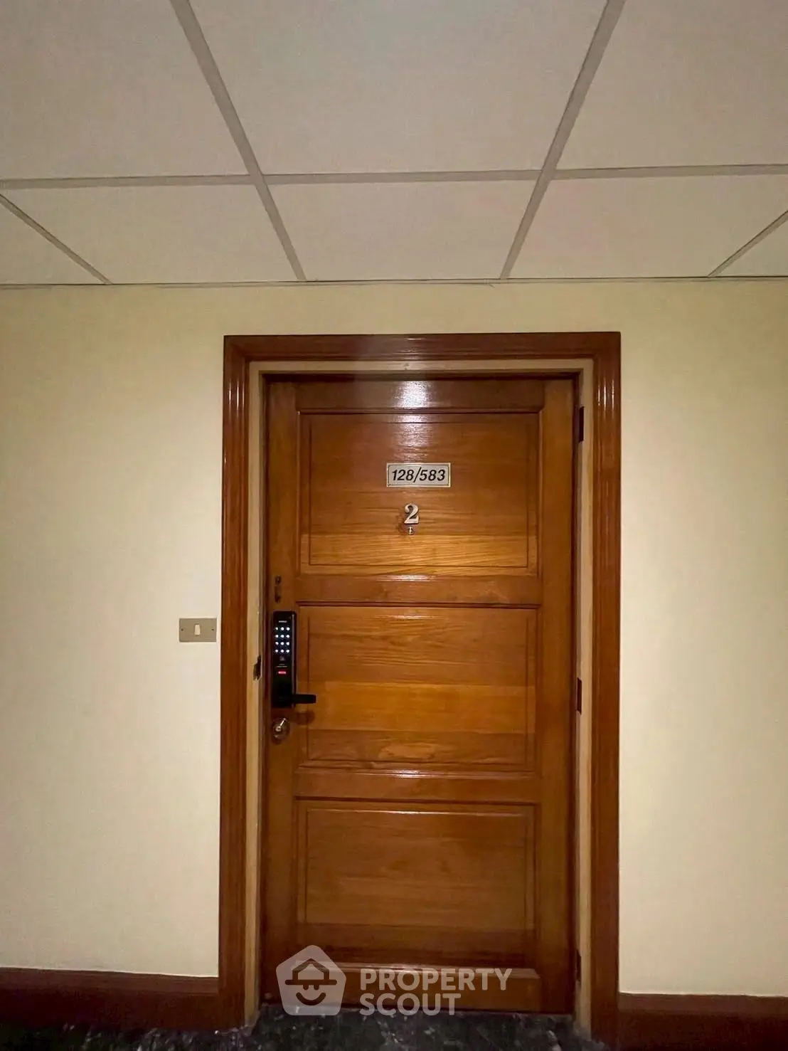 Elegant wooden apartment door with electronic lock in modern building hallway.