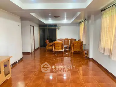 Spacious living room with wooden furniture and tiled flooring, perfect for family gatherings.